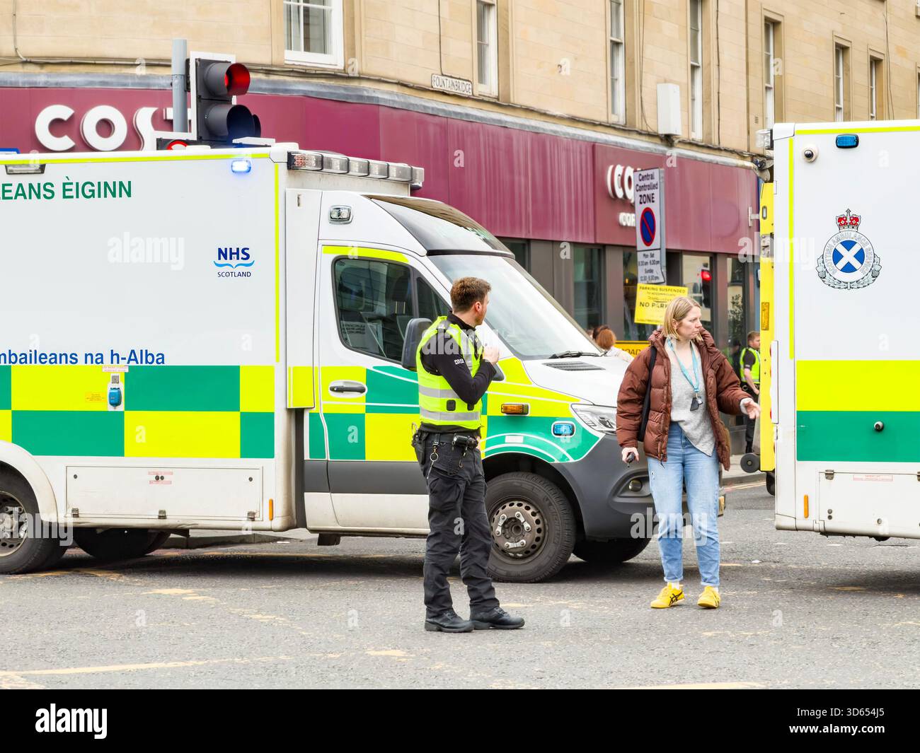 Scottish emergency ambulances & crew respond to an accident at Edinburgh street junction with in front of a Costa Coffee shop - Smartphone Captured Stock Image