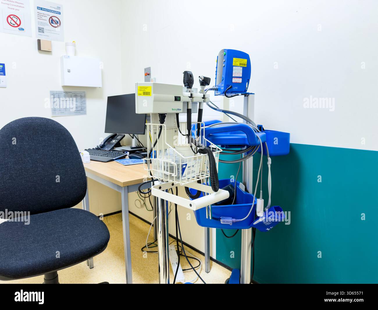 Medical consultation room with diagnostic equipment, computer workstation, chair, and clinical monitoring devices in a hospital healthcare setting - Smartphone Captured Stock Image