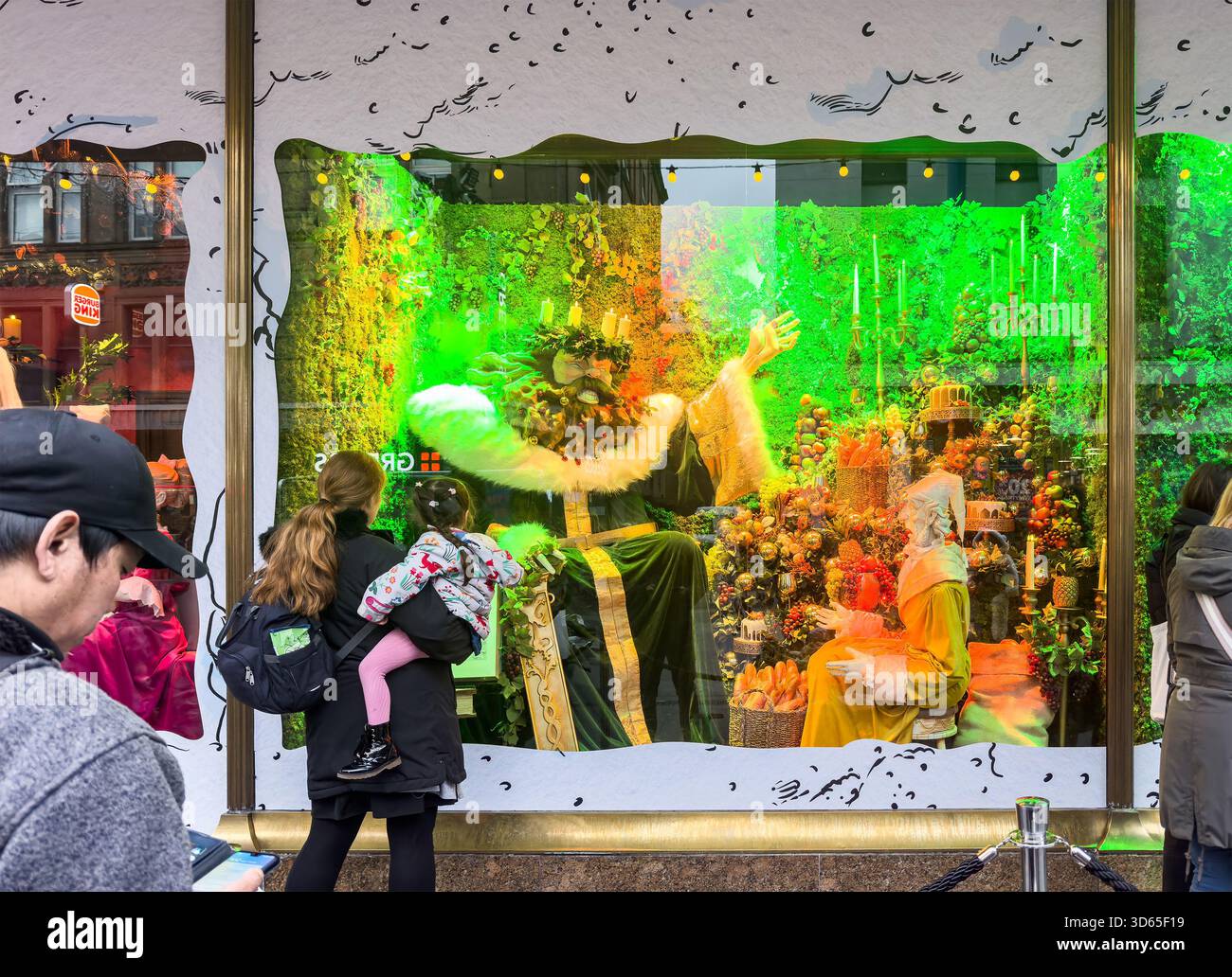 People admire an elaborate christmas holiday-themed Fenwicks department store window display  & festive characters and a vibrant feast scene newcastle - Smartphone Captured Stock Image