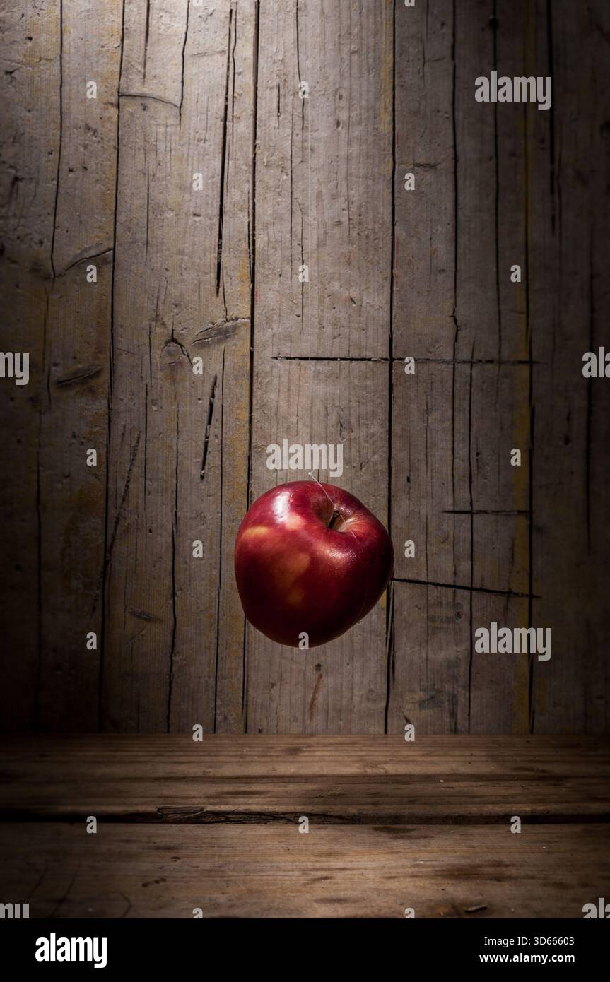 Apple floats in front of wood texture, zenithal light above highlights ...