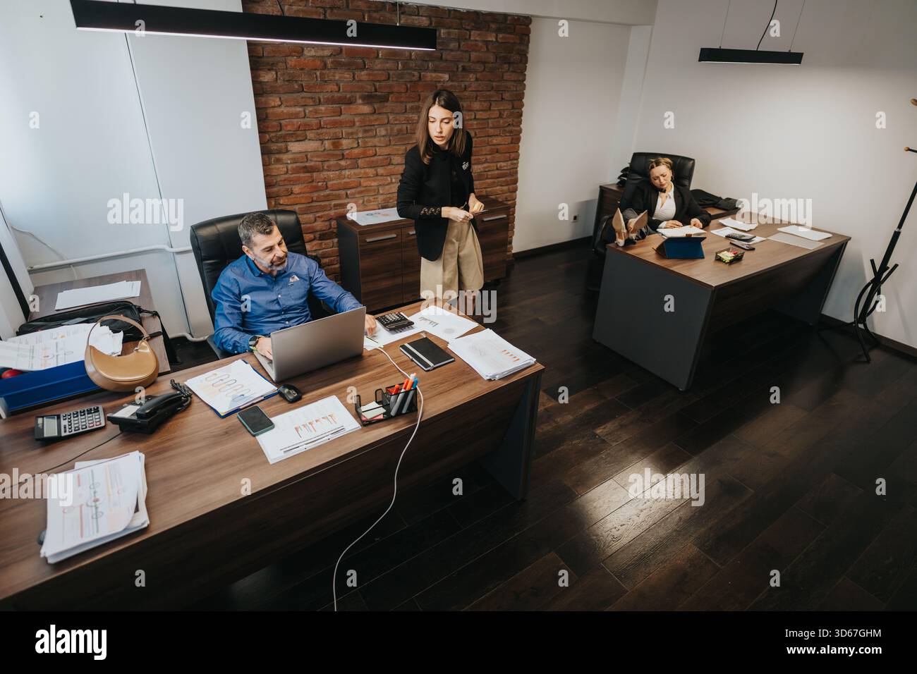 Three professionals collaborating in a modern office setting with documents Stock Photo