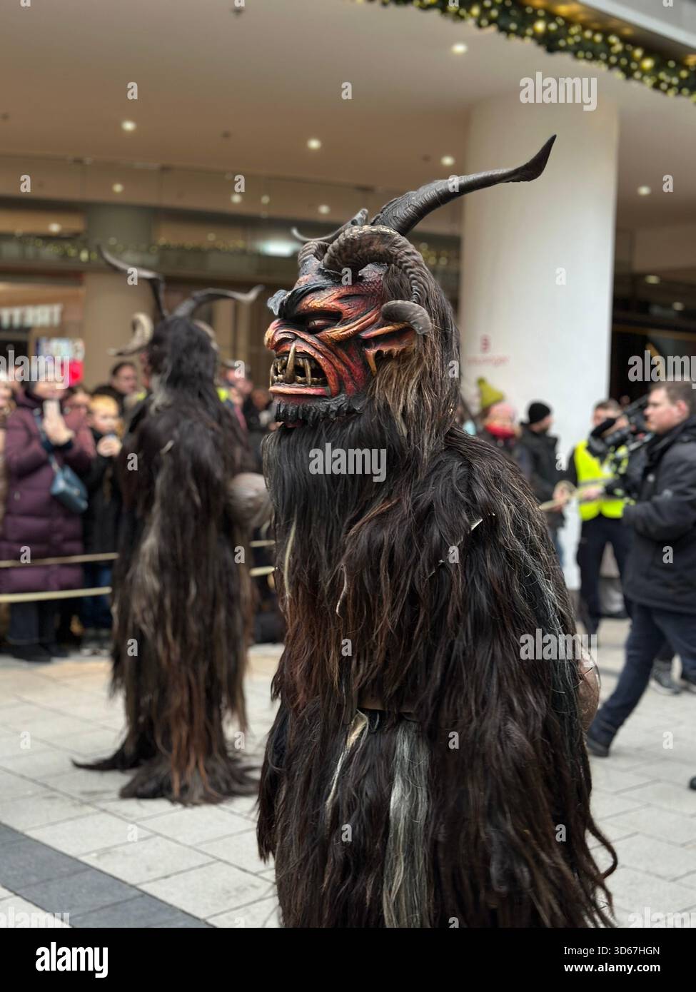 Krampus festival parade in Munich, Germany, during the 2024 Christmas season. Costumed Krampus performers in traditional fur suits and horned masks - Smartphone Captured Stock Image