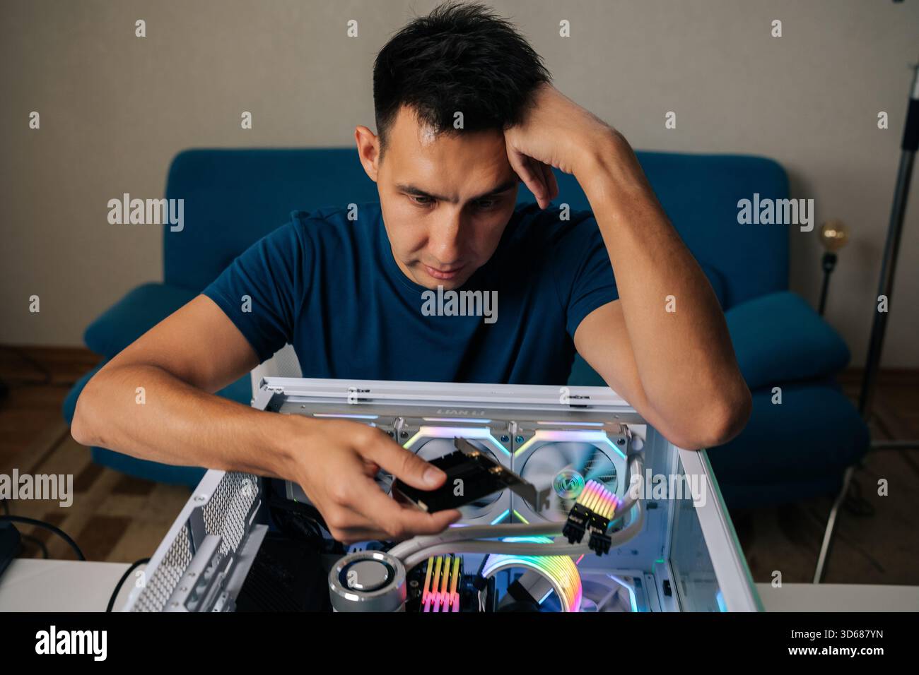 Portrait of puzzled technician upgrading desktop computer by installing wi-fi module, focusing intently on task with thoughtful expression, showcasing Stock Photo