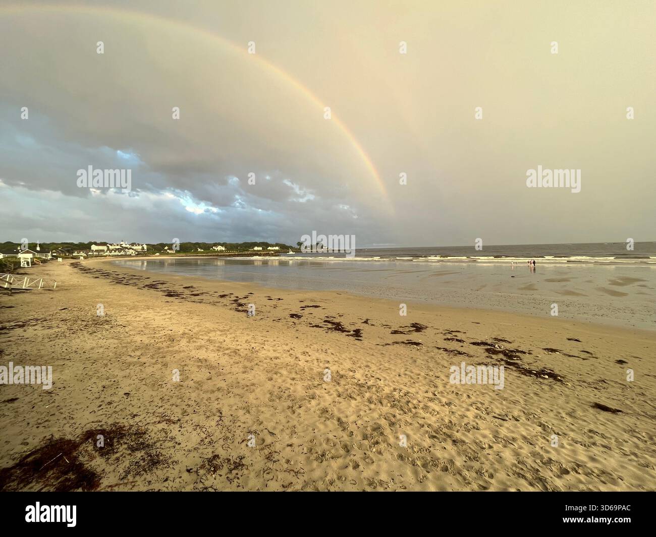 A rainbow in the sky above a sandy beach in the early evening of a summer day. - Smartphone Captured Stock Image