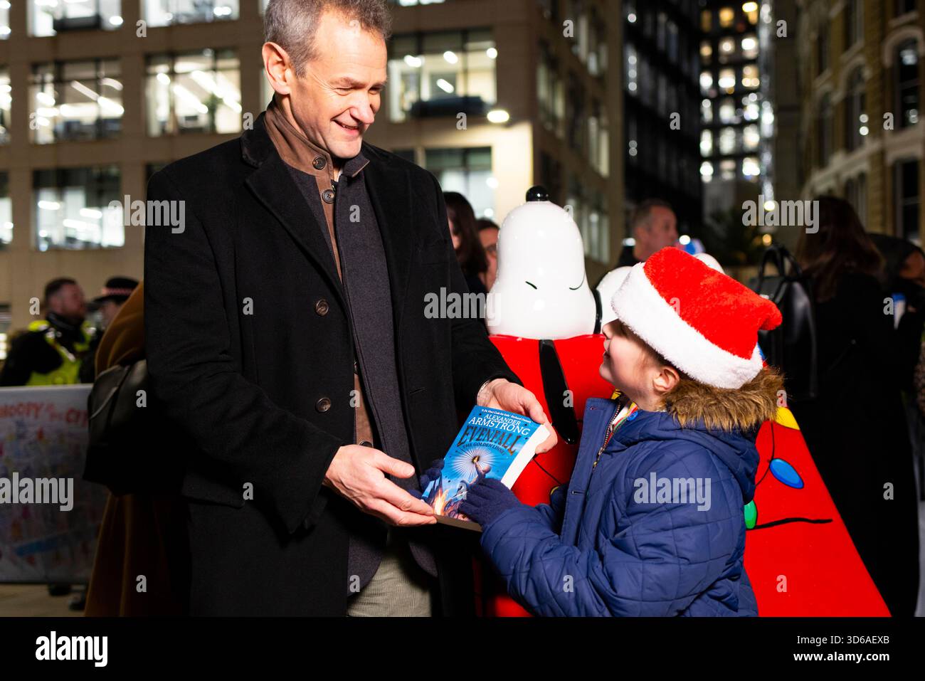 EDITORIAL USE ONLY Alexander Armstrong hands a copy of his book to Cecily aged 7 as he starts the Christmas celebrations in Fleet Street Quarter, marking the launch of the area's partnership with the National Literacy Trust and debut of it's 'Snoopy in the City' Sculpture Trail as part of Peanuts' 75th anniversary, London. Issue date: Wednesday 19 November, 2025. Stock Photo