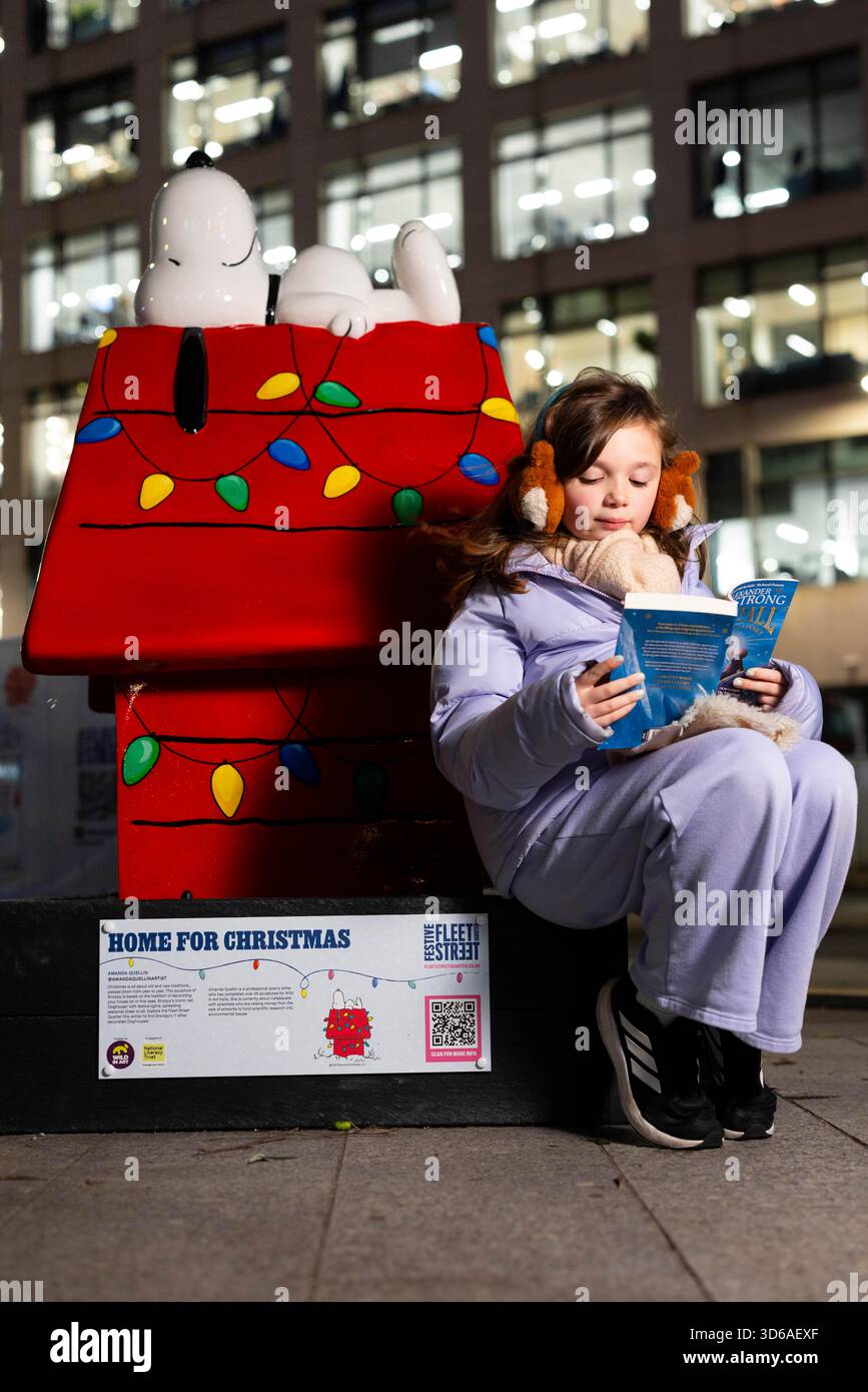 EDITORIAL USE ONLY Athena aged nine reads with the 'Snoopy in the City' Sculpture Trail, part of the Christmas celebrations in Fleet Street Quarter, marking the launch of the area's partnership with the National Literacy Trust and debut of it's 'Snoopy in the City' Sculpture Trail as part of Peanuts' 75th anniversary, London. Issue date: Wednesday 19 November, 2025. Stock Photo