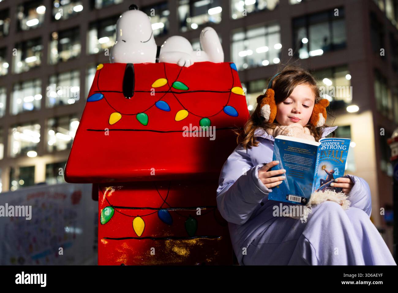EDITORIAL USE ONLY Athena aged nine reads with the 'Snoopy in the City' Sculpture Trail, part of the Christmas celebrations in Fleet Street Quarter, marking the launch of the area's partnership with the National Literacy Trust and debut of it's 'Snoopy in the City' Sculpture Trail as part of Peanuts' 75th anniversary, London. Issue date: Wednesday 19 November, 2025. Stock Photo