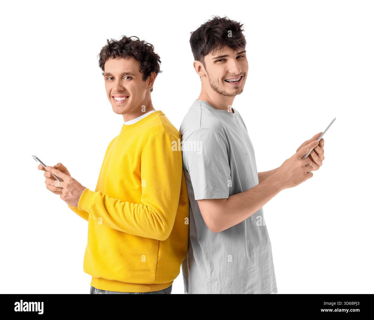 Young brothers using mobile phone and tablet computer on white background Stock Photo