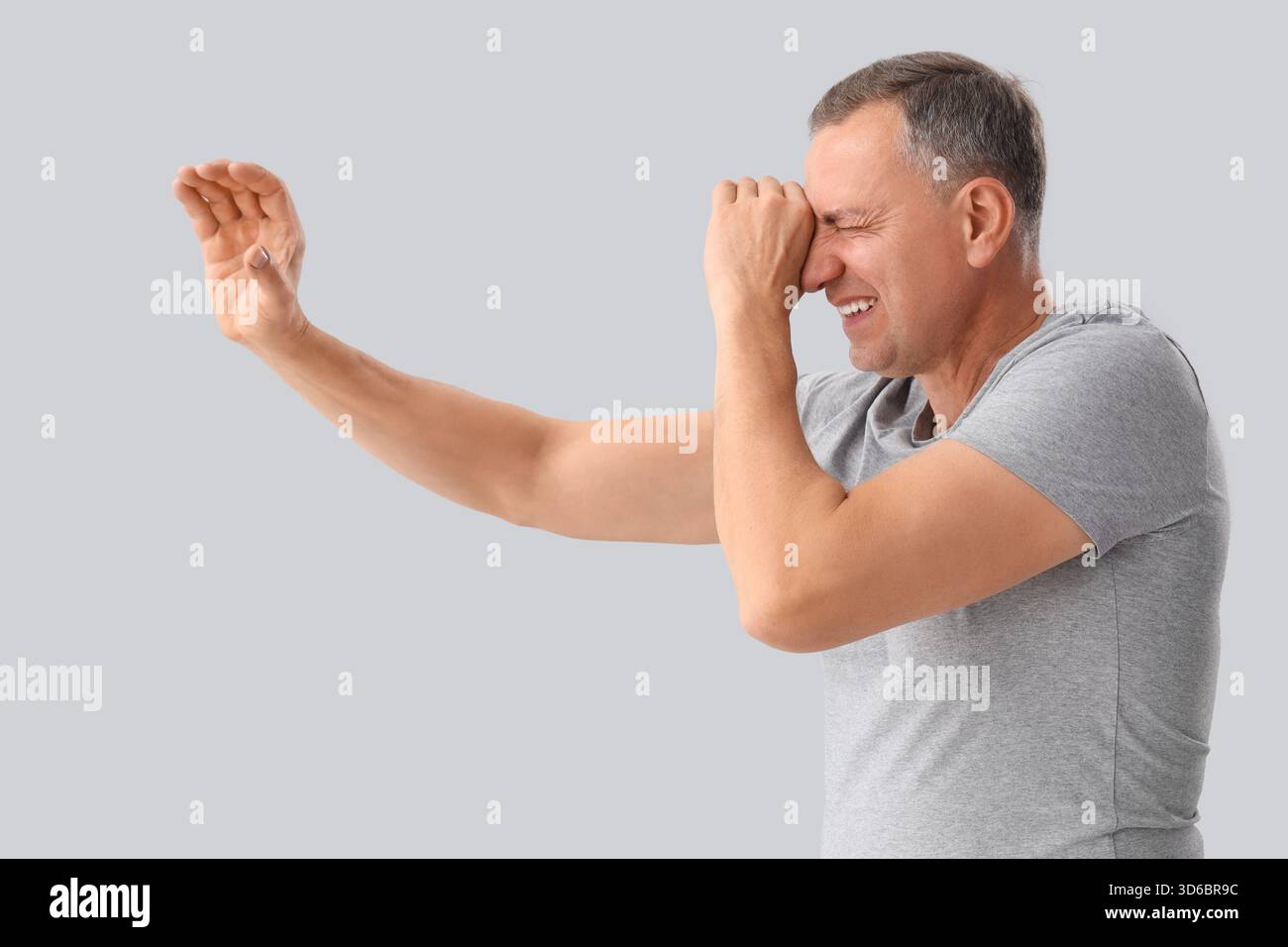 Mature man looking through imaginary telescope on light background Stock Photo