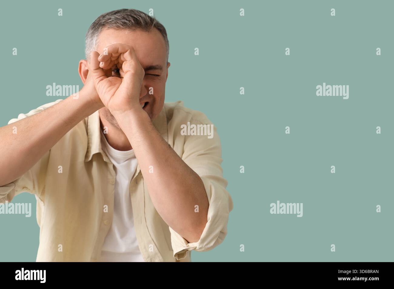 Mature man looking through imaginary telescope on green background Stock Photo