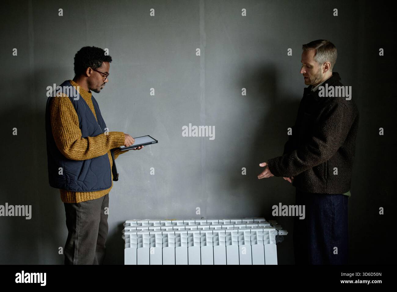 Middle Aged Black Man Using Digital Tablet While Caucasian Man Explaining Stock Photo
