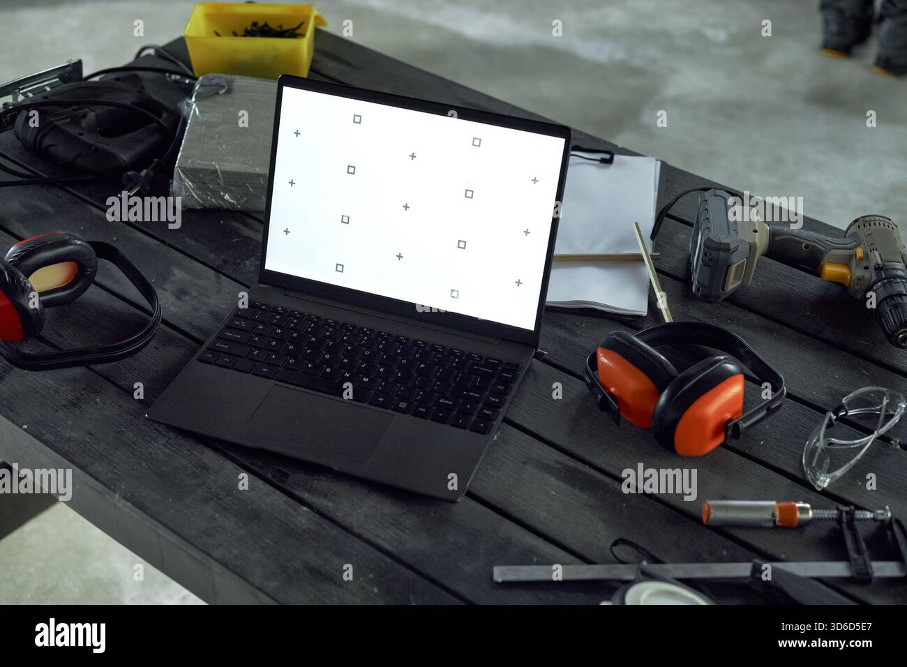 Laptop Displaying Calibration Screen on Workshop Table Surrounded by Tools Stock Photo