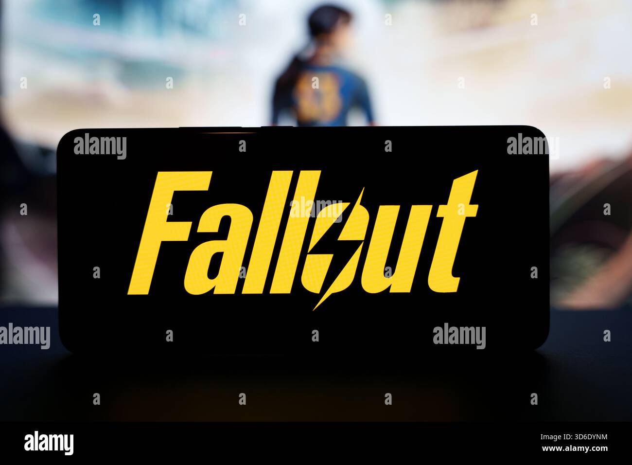Fallout TV series logo on smartphone screen with blurred character background. High quality photo Stock Photo