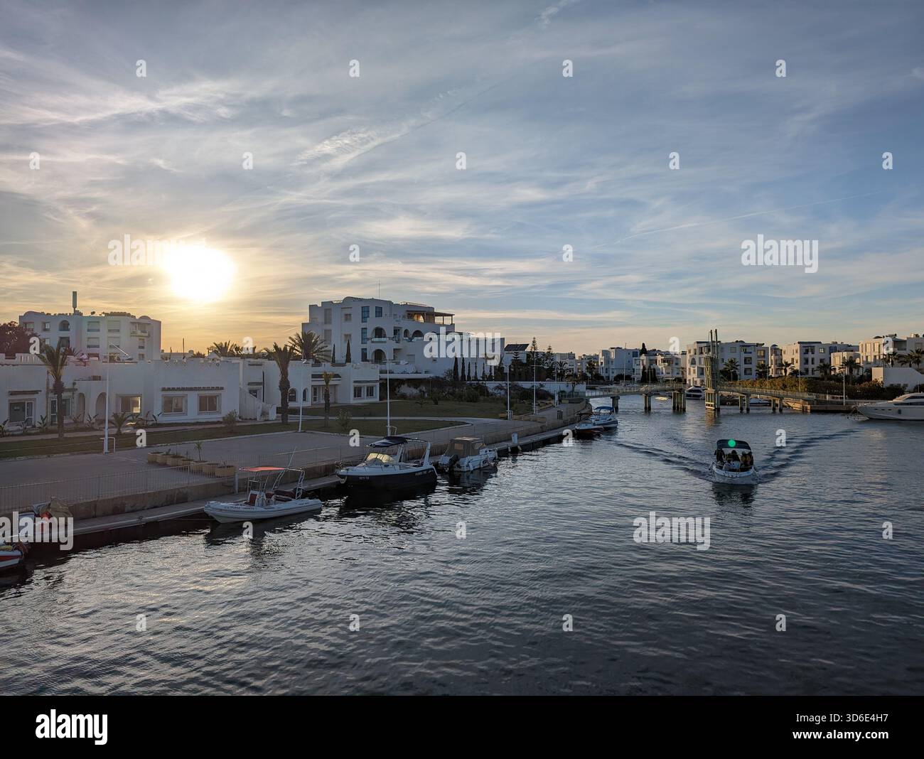 Sunset over the marina in Hammamet, Tunisia, with boats and Mediterranean-style architecture - Smartphone Captured Stock Image