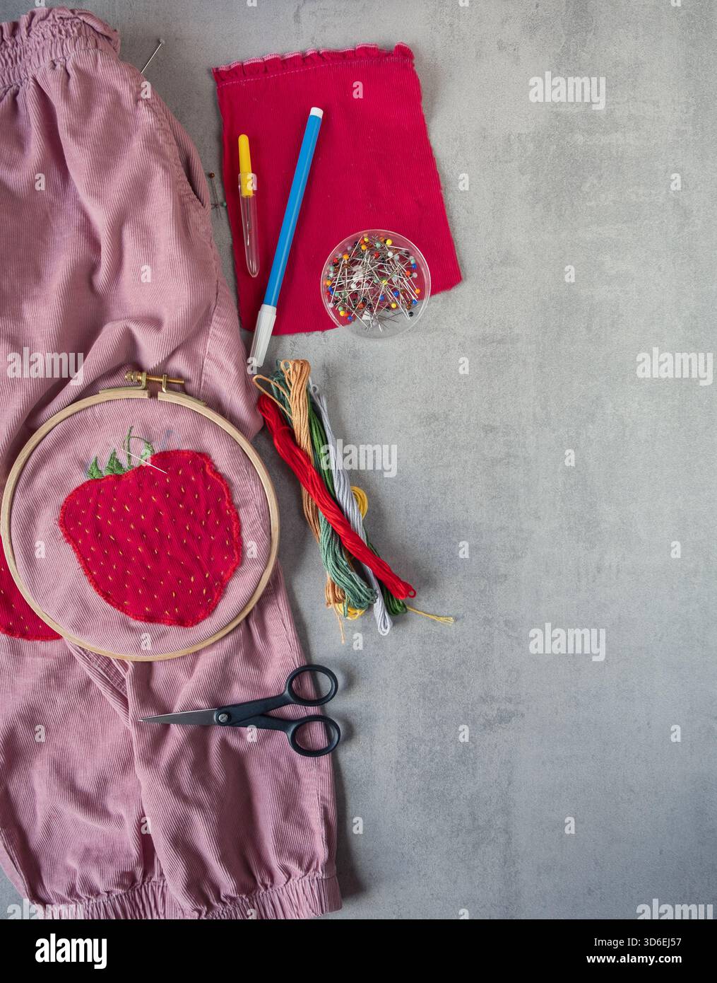 Children’s corduroy trousers with a strawberry patch placed beside ...