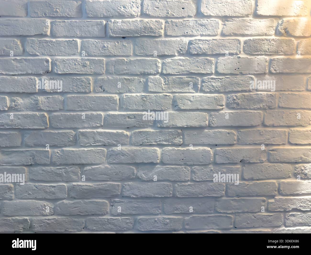 White brick wall under soft afternoon lighting, textured surface and subtle shadows Stock Photo