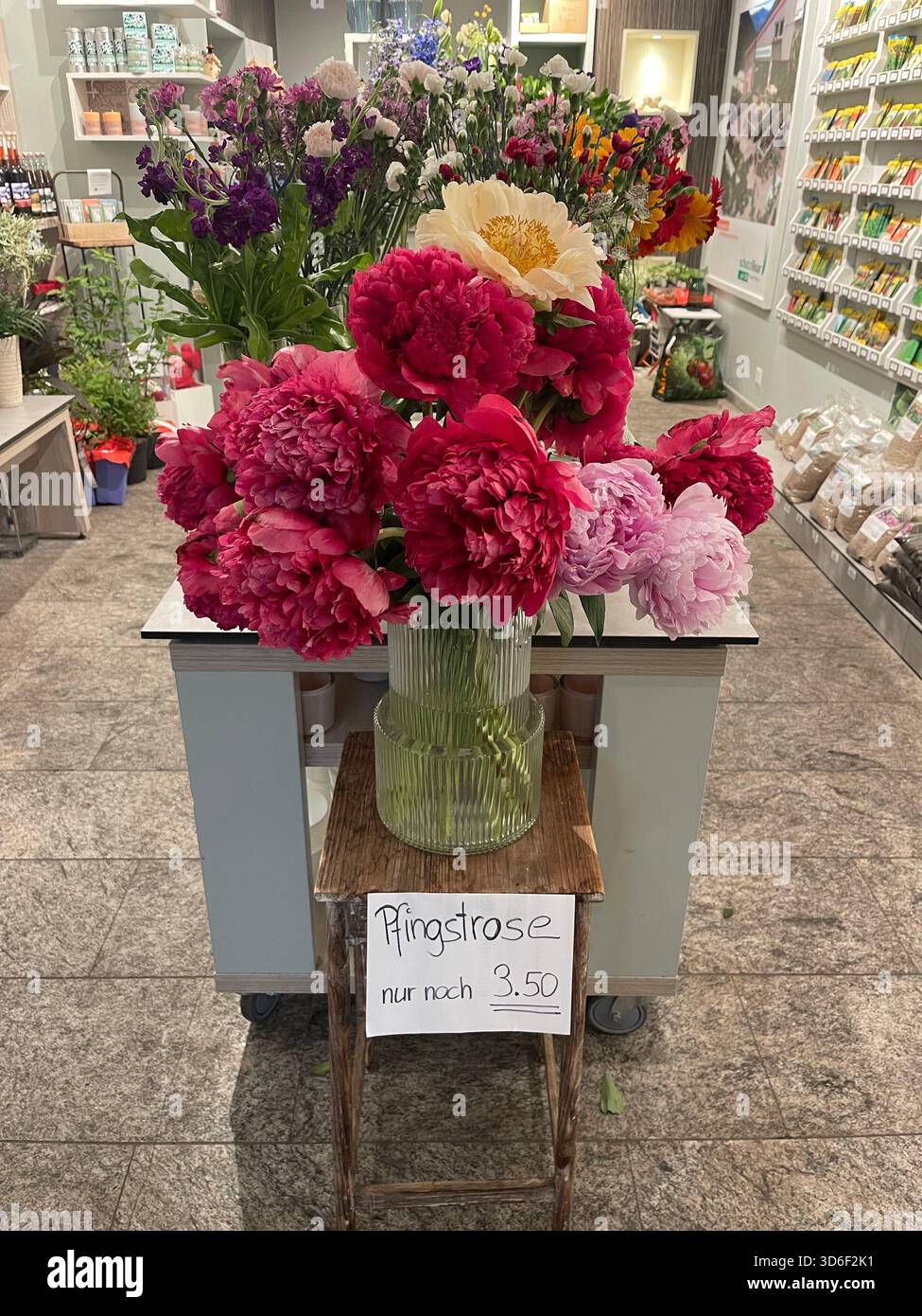 Fresh peonies displayed in a flower shop. Soft, delicate petals and rich texture highlighted by natural light create an atmosphere of refined beauty. - Smartphone Captured Stock Image
