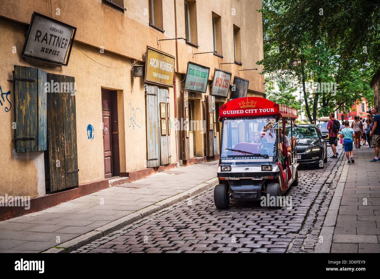 Small open-air Guided City Tour cart on narrow street in Krakow Jewish Quarter in Kraków, Poland. Stock Photo
