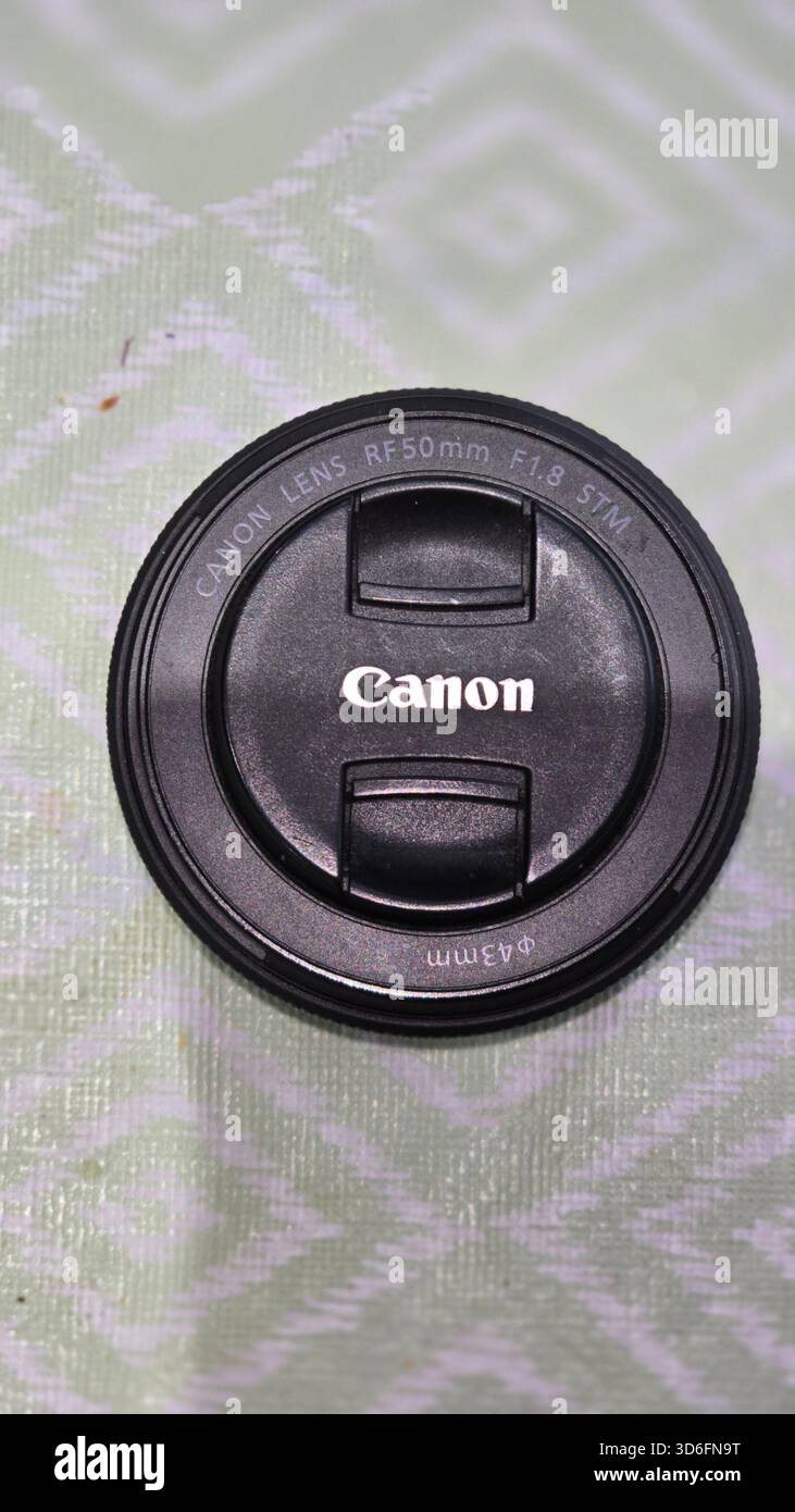 Canon 50mm lens rests on a patterned surface with shallow depth of field, highlighting its AF/MF switch and sleek design. - Smartphone Captured Stock Image