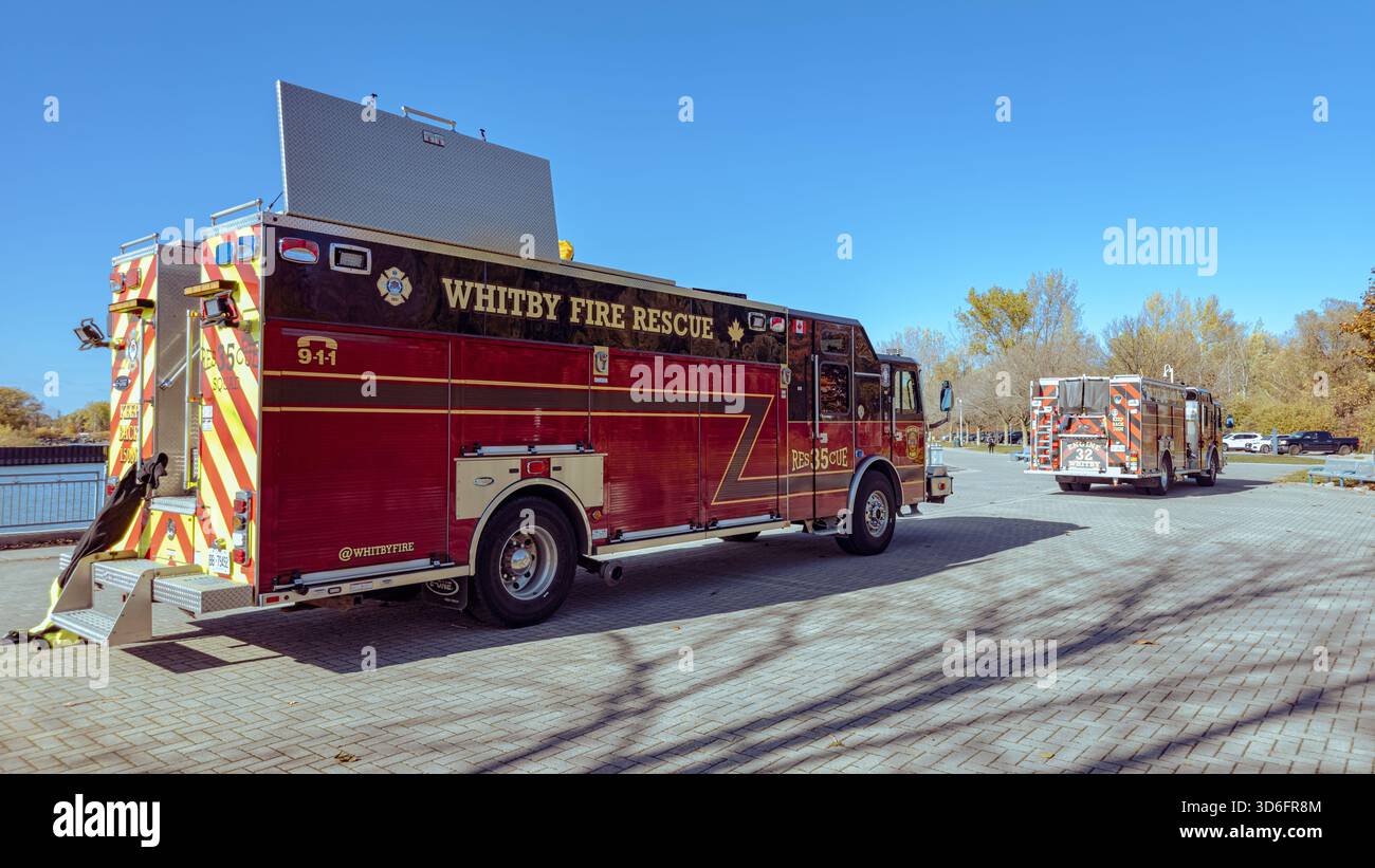 Two red Whitby Fire Rescue trucks parked near Ontario lake under a clear blue sky, ready for emergency response. - Smartphone Captured Stock Image