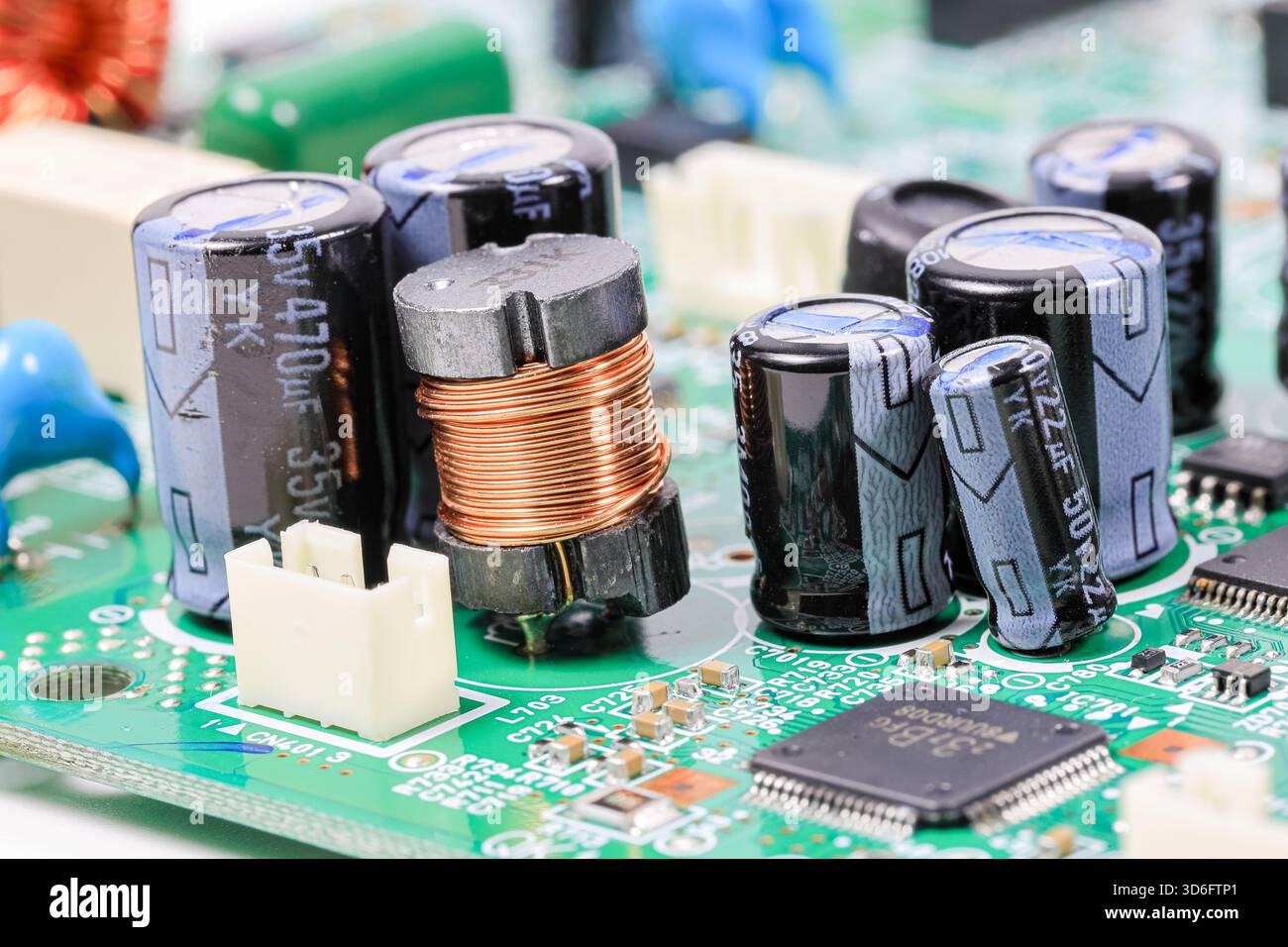 Electromagnetic components produced from copper element and many of capacitors on electronic circuit. Stock Photo