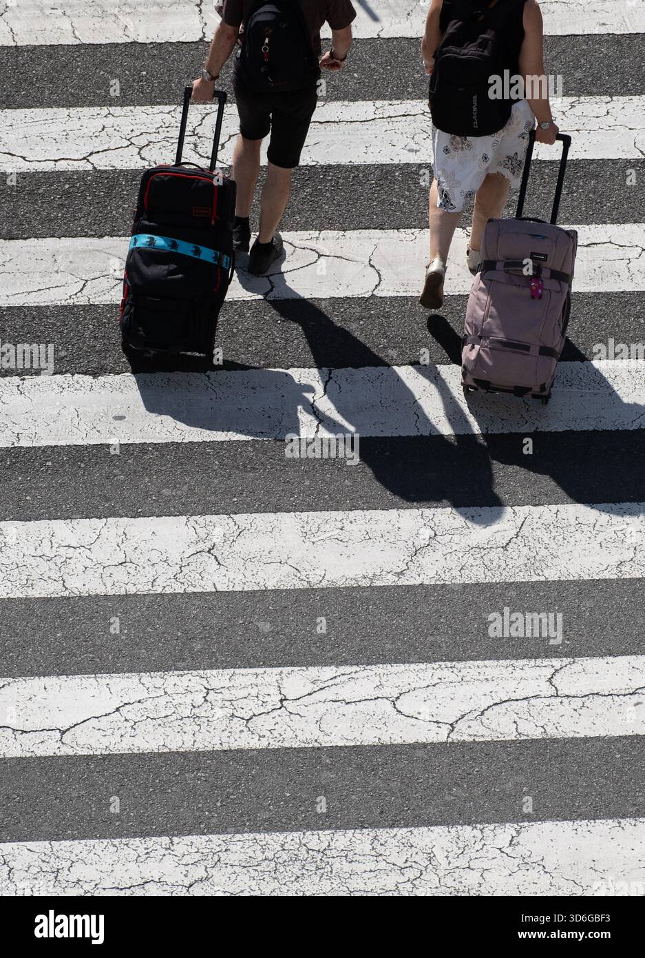Tourists with luggage, wheeled suitcase crossing pedestrian crossing in Spain Stock Photo