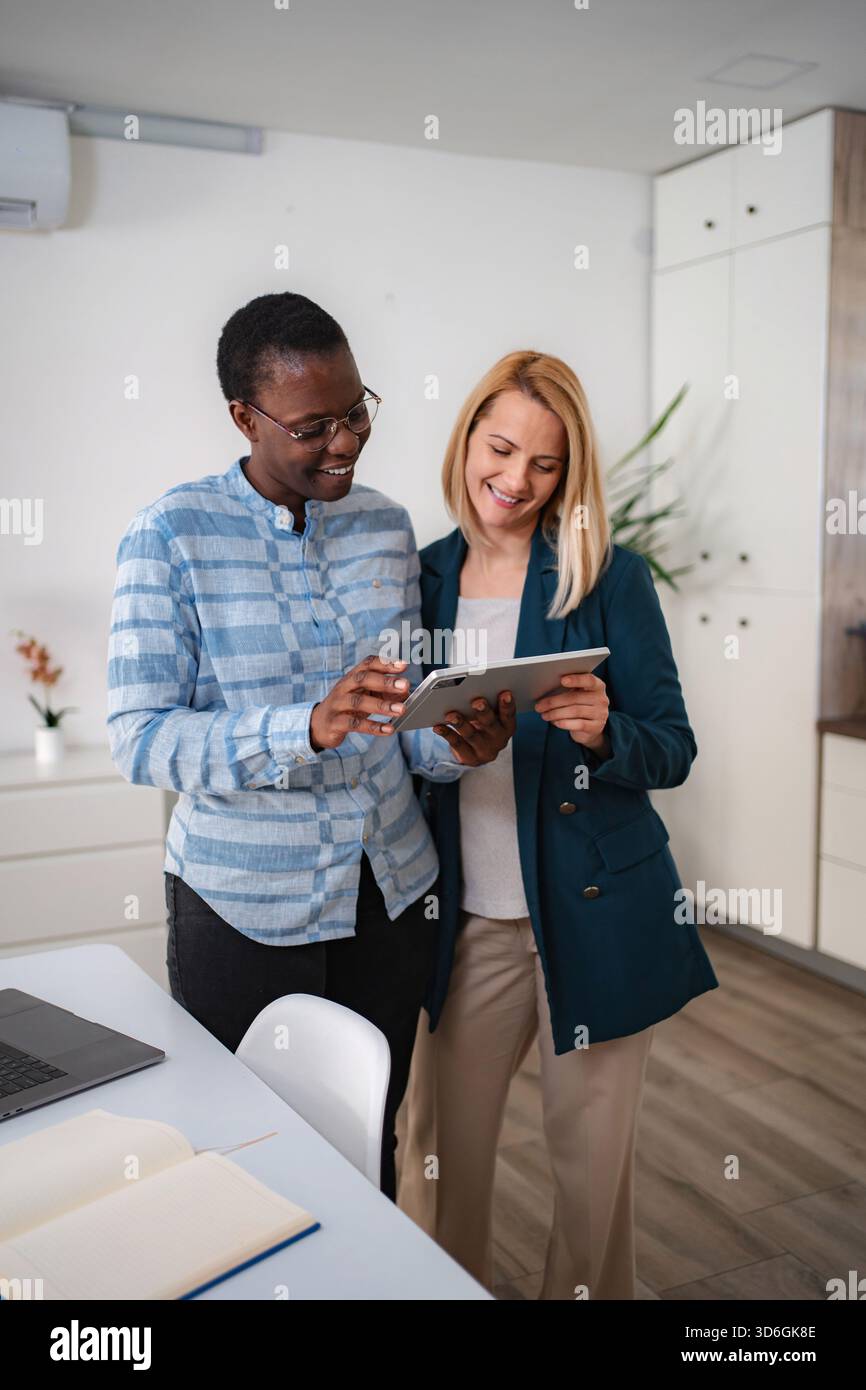 Diverse women colleagues collaborating on digital tablet in office Stock Photo