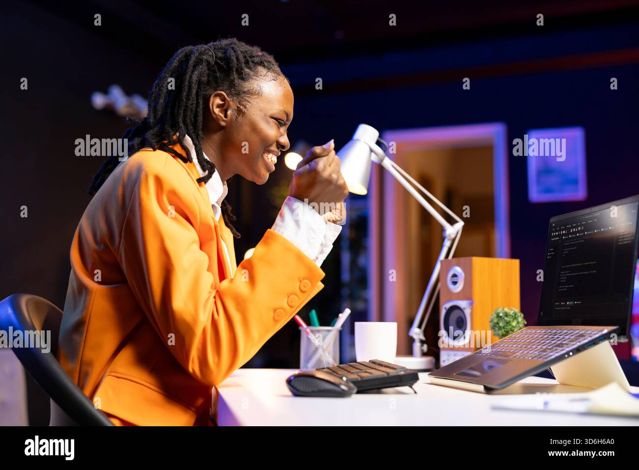 Happy developer at laptop programming, exuberating after writing lines of code, using development tools. Ecstatic woman in home office pleased after finishing debugging software on notebook Stock Photo