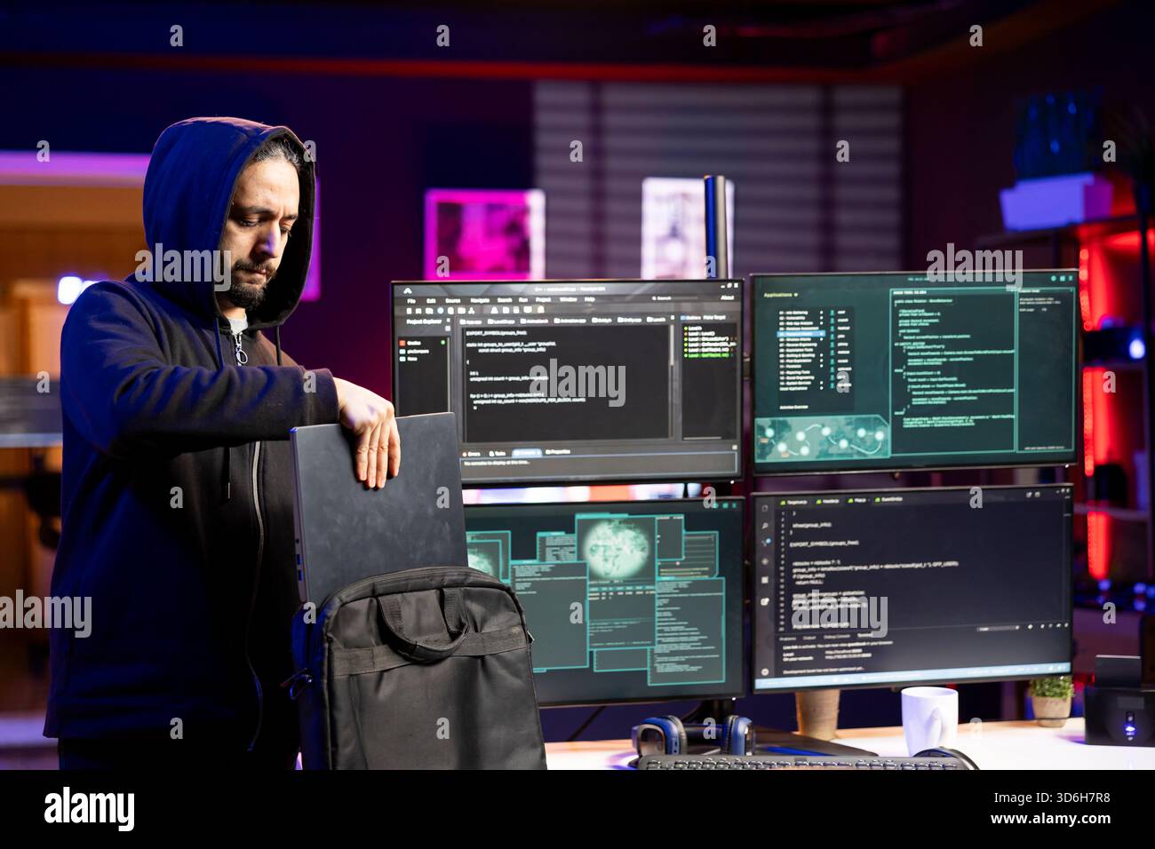 Hacker packing laptop after finishing coding stealth malware to evade security. Evil man putting notebook in backpack after finishing work on script hiding malicious code from detection systems Stock Photo