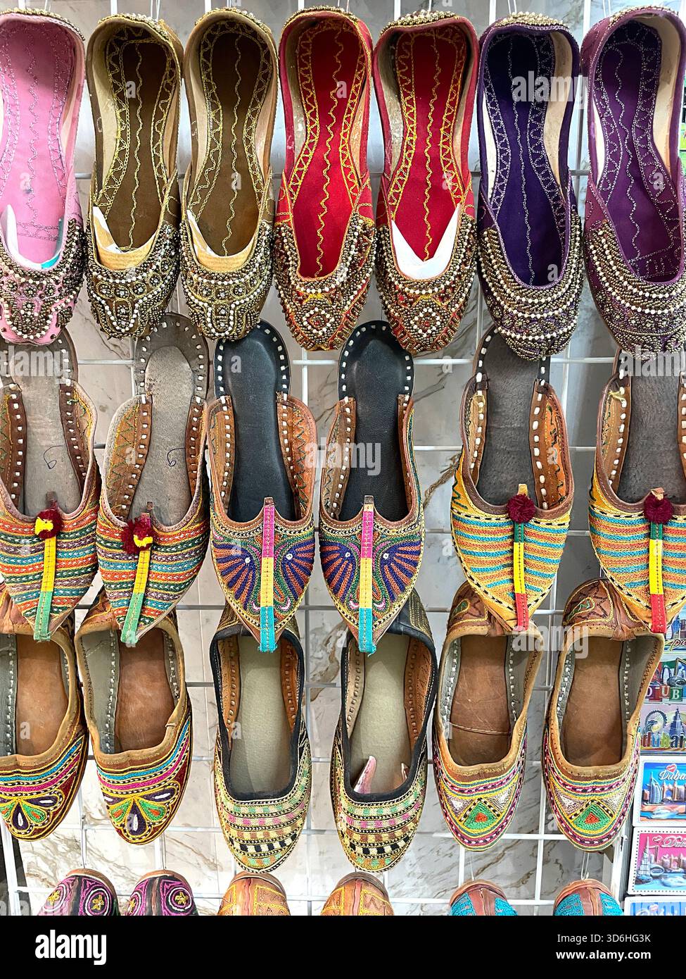 Colourful traditional handcrafted Indian shoes display on market wall in assortment of intricate patterns & embroidered designs deira creek duba UAEi - Smartphone Captured Stock Image