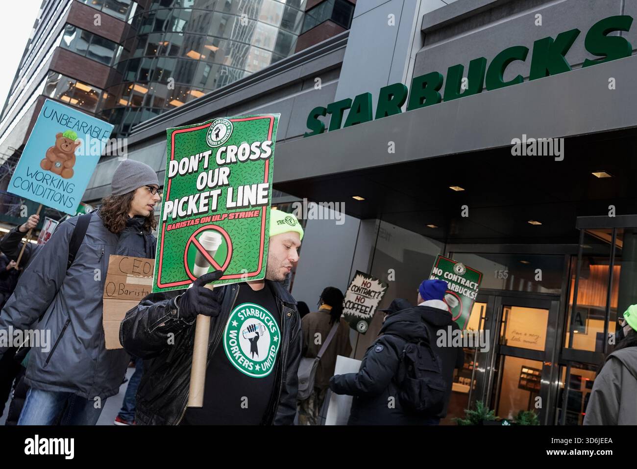 Starbucks baristas and employees picket outside a Starbucks storefront