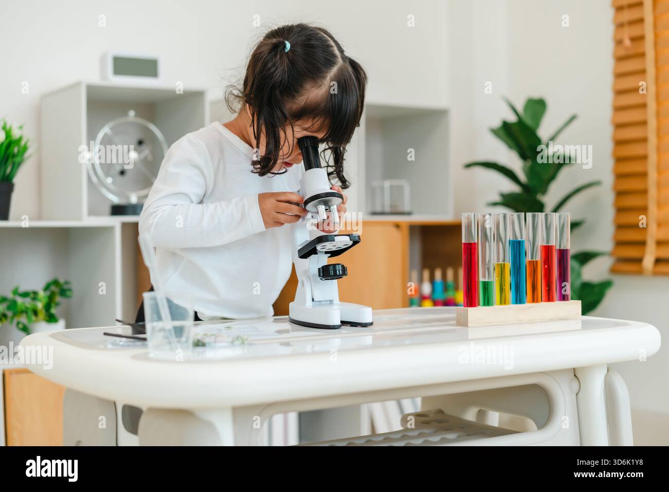 toddler girl scientist looking through a microscope. learning science Stock Photo