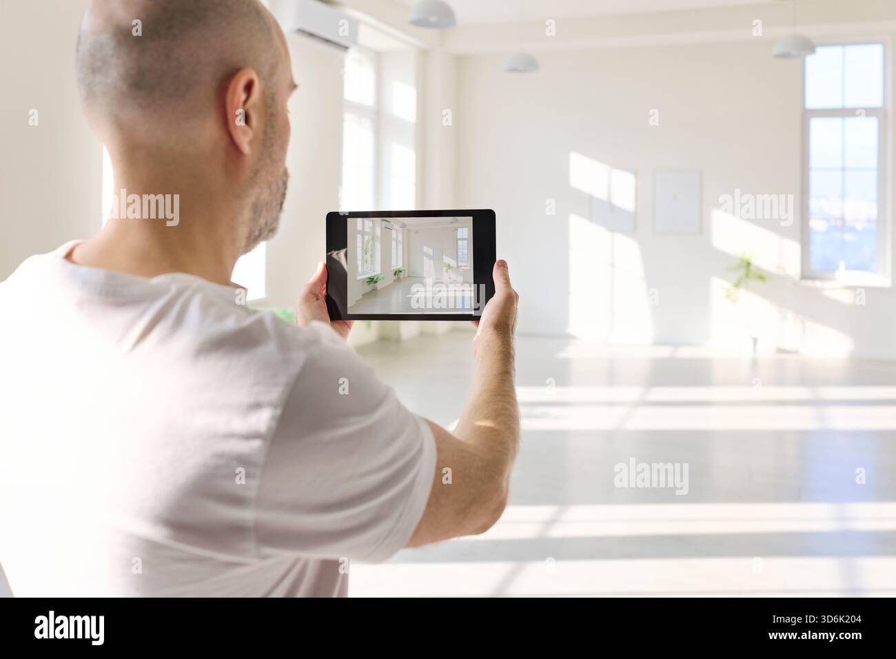 Designer using tablet to visualize interior layout in empty hall with ...