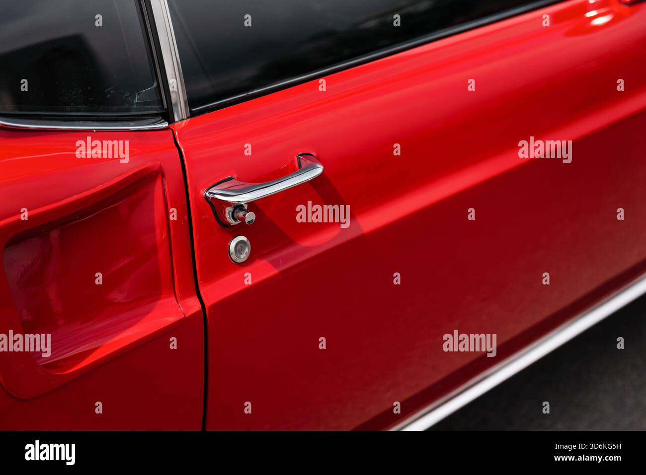 Door handle of old red car. Shiny chrome door handle of classic coupe - 1960s muscle car exterior Stock Photo