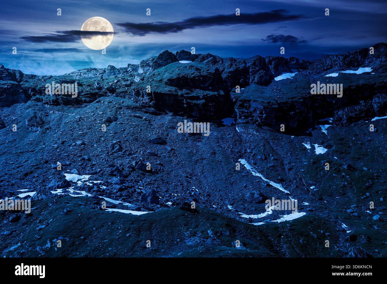 mountain landscape in summer at night. ridge under blue sky with clouds in full moon light. alpine scenery with rocky peaks and steep slopes. horizont Stock Photo