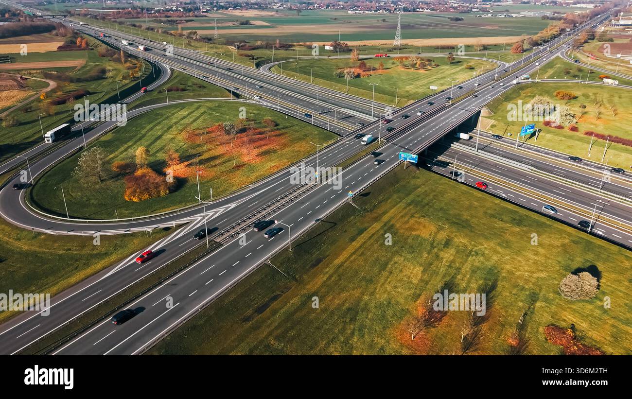 Aerial highway junction road interchange infrastructure countryside. Top-down drone view of multilane expressway intersection surrounded by fields, ve Stock Photo