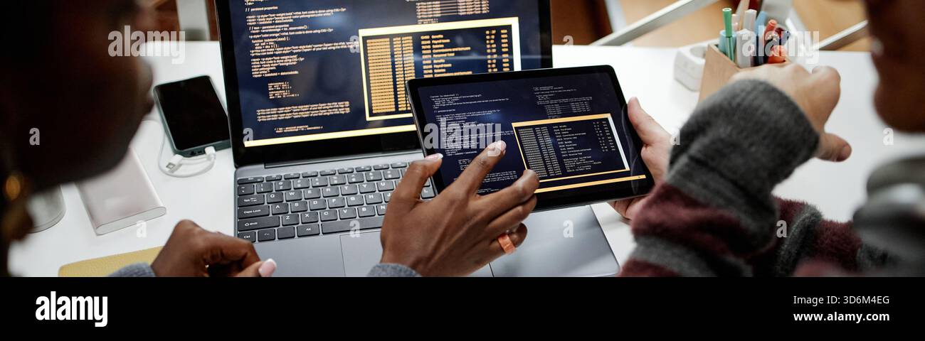 Header of Multiethnic Colleagues Reviewing Software Code on Tablet in Office Stock Photo