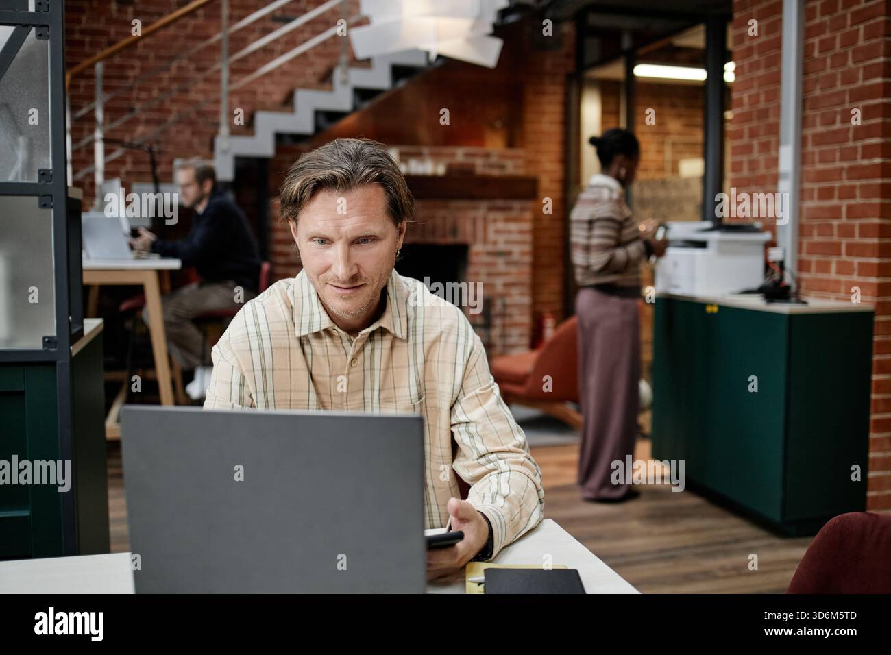 Caucasian Middle Aged Man Using Laptop While Colleagues Working in Office Stock Photo