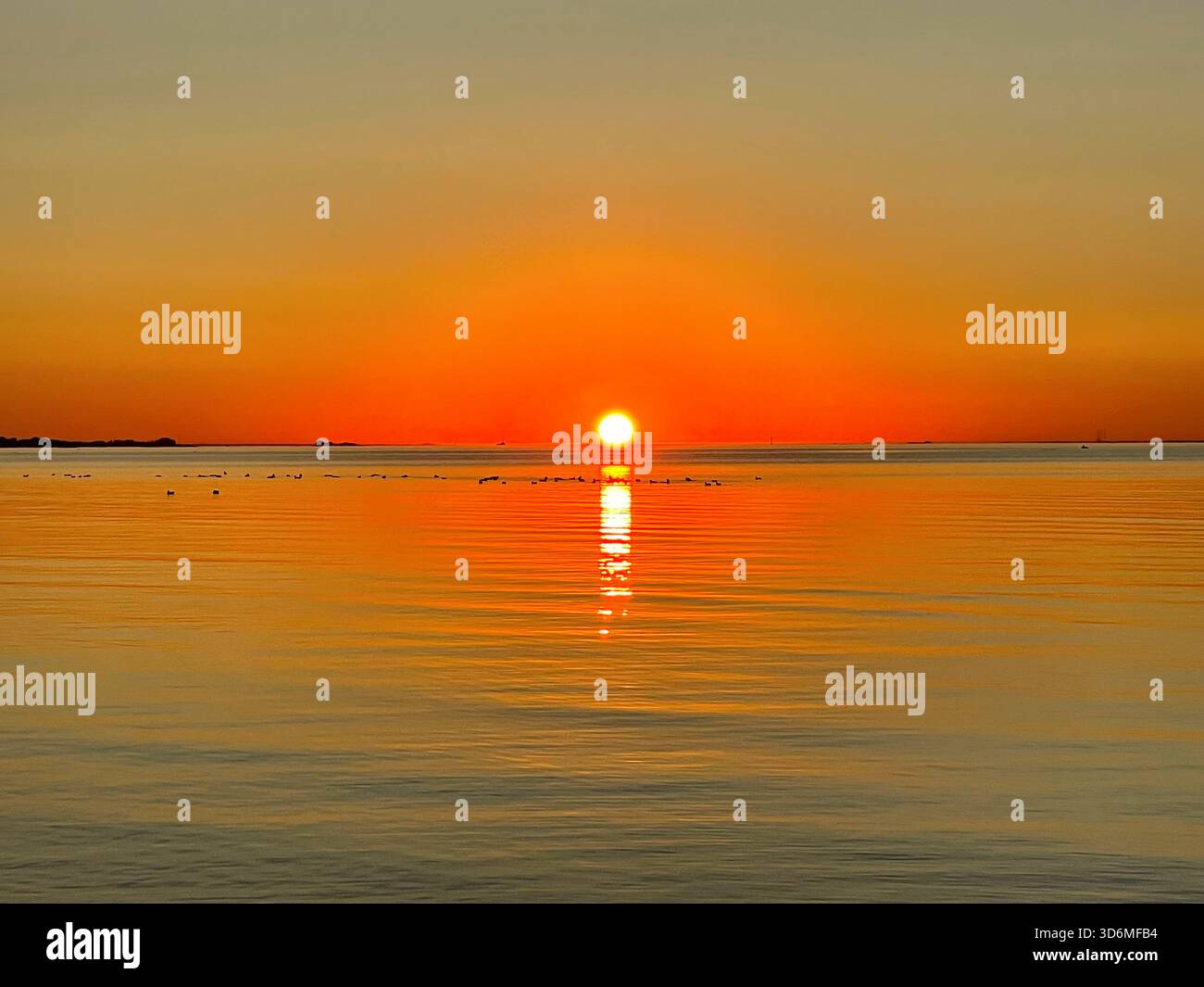 Beautiful sunset over the sea. Bright sun touches the horizon, painting ...