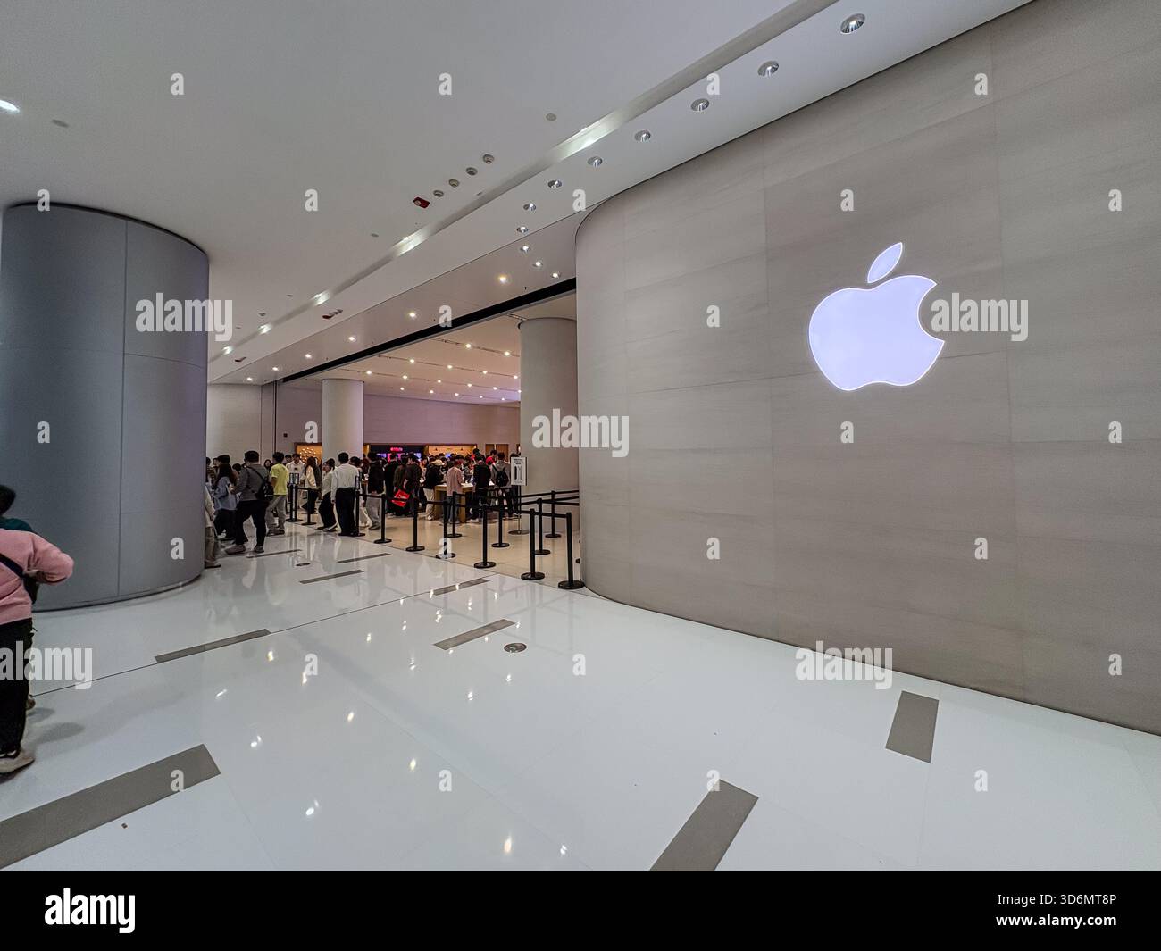 Apple Store in a modern shopping mall features its iconic glowing logo ...