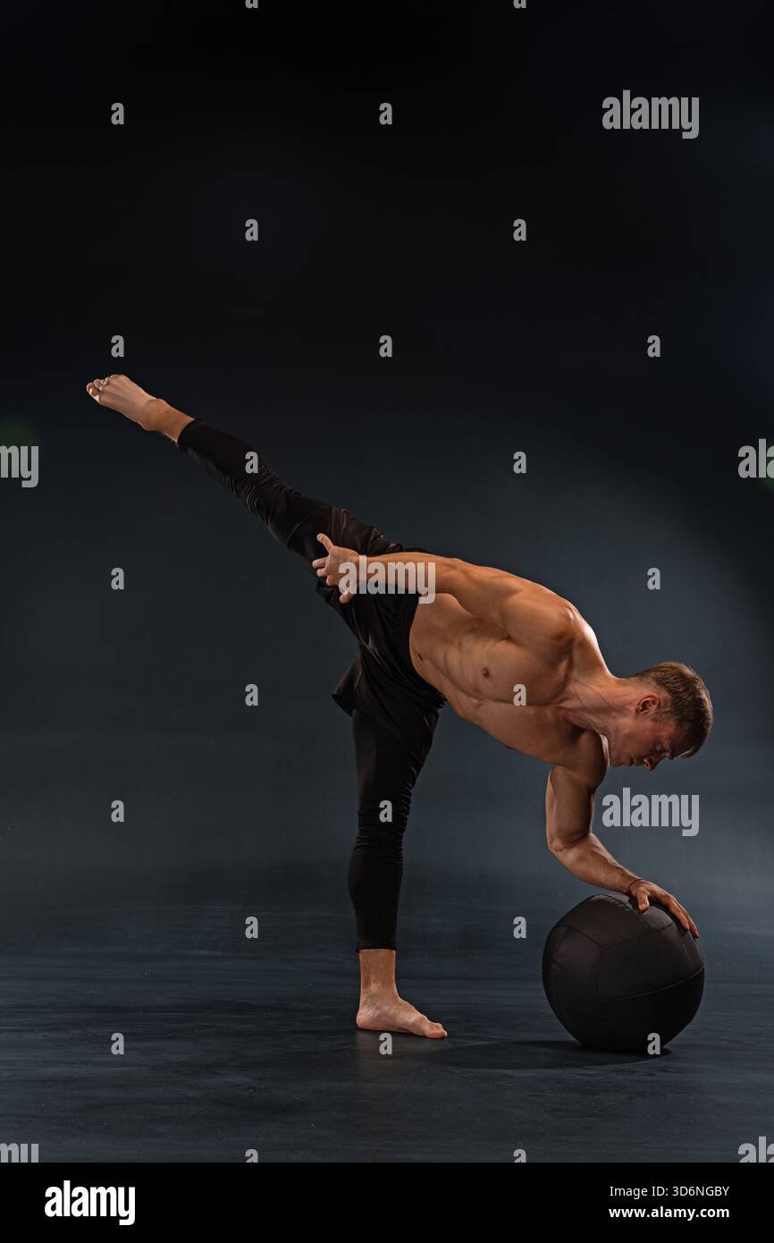 male dancer performs an impressive pose. He balances on one leg while ...