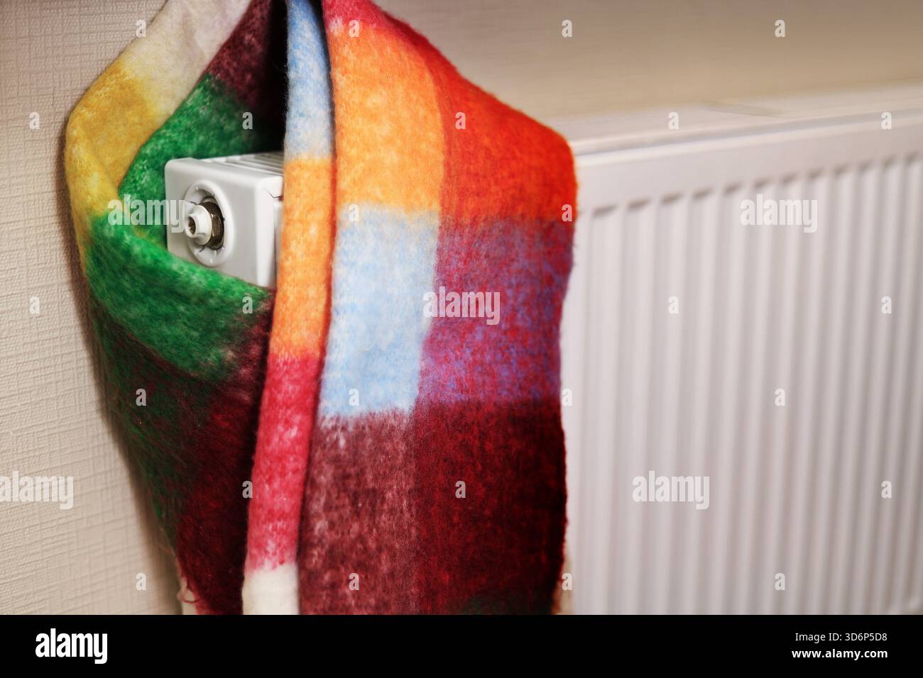 a radiator wrapped in a multi-colored scarf, symbolizing the cold in the room. High quality photo Stock Photo