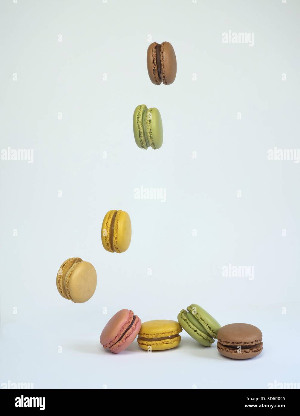 Colored macaroons falling in a row on a white table with copy space Stock Photo
