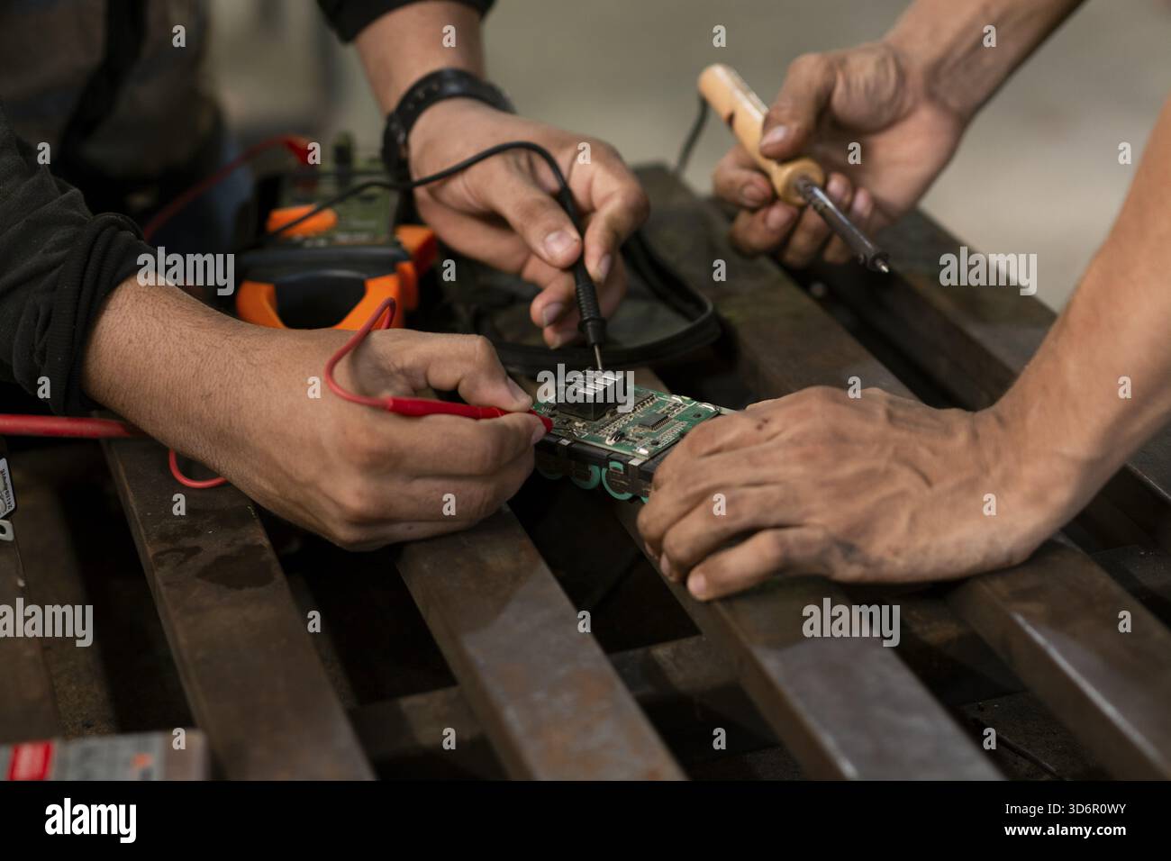 Close-up of two man using a soldering iron on an electronic circuit board on a table Stock Photo