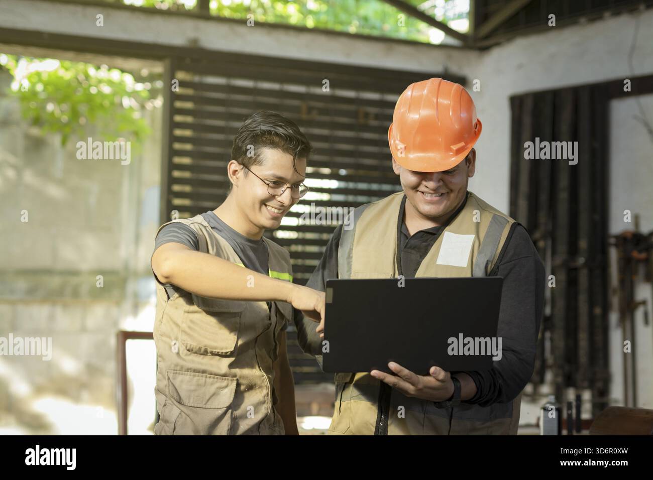 Carpentry boss showing computer to colleague in the workshop. Carpentry Workshop manager using the computer to teach a worker Stock Photo