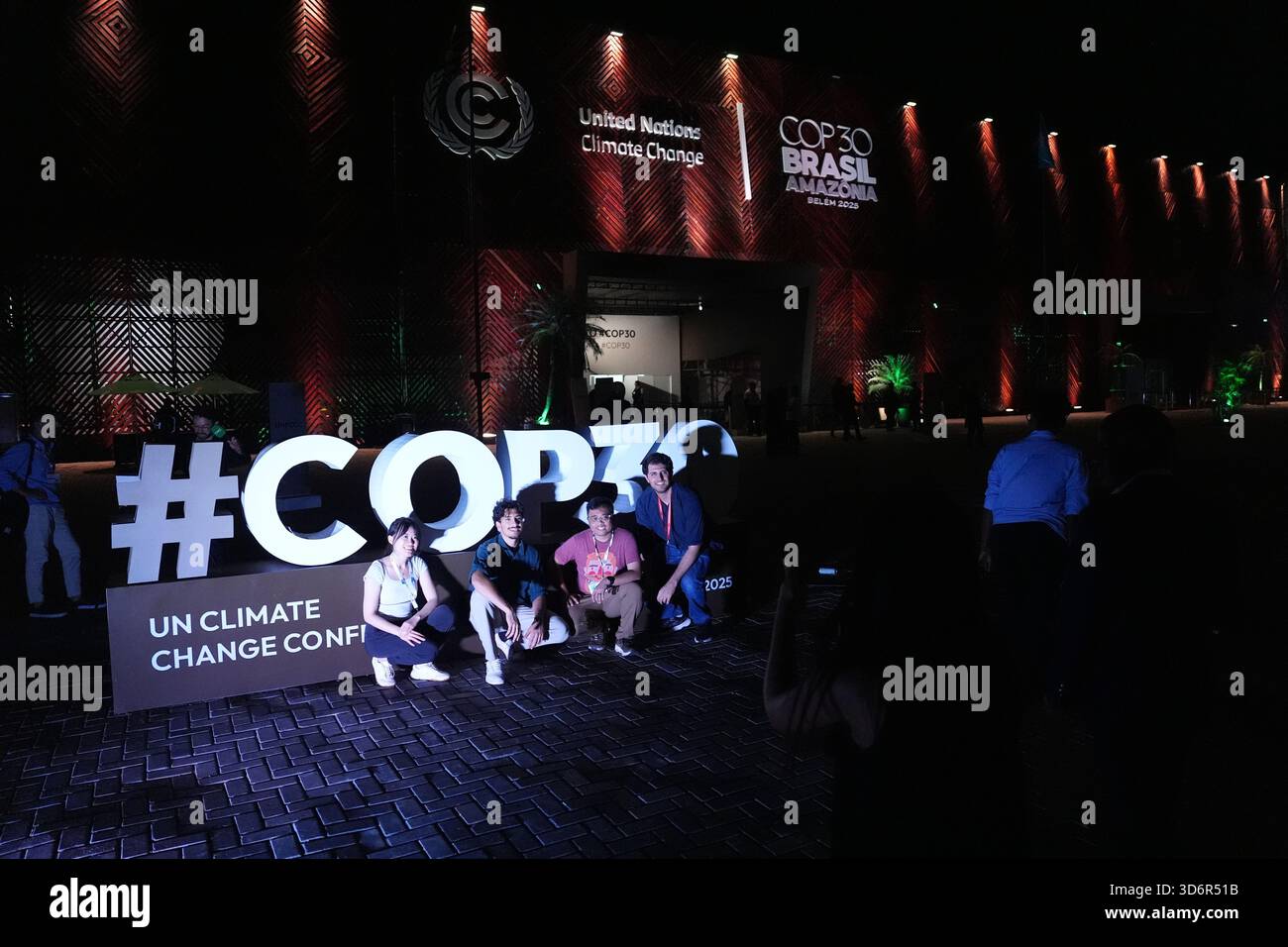 People pose for photos outside the venue for the COP30 U.N. Climate ...