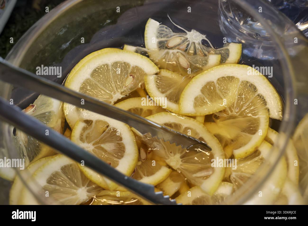 Refreshing glass bowl filled with fresh sliced lemon for healthy drink. vibrant yellow citrus fruit and juicy pulp create zesty background for food an Stock Photo