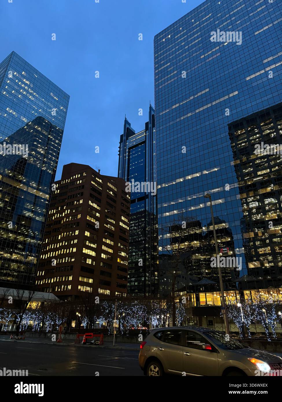 Evening view of downtown Calgary with illuminated office skyscrapers and reflective glass buildings during blue hour. - Smartphone Captured Stock Image