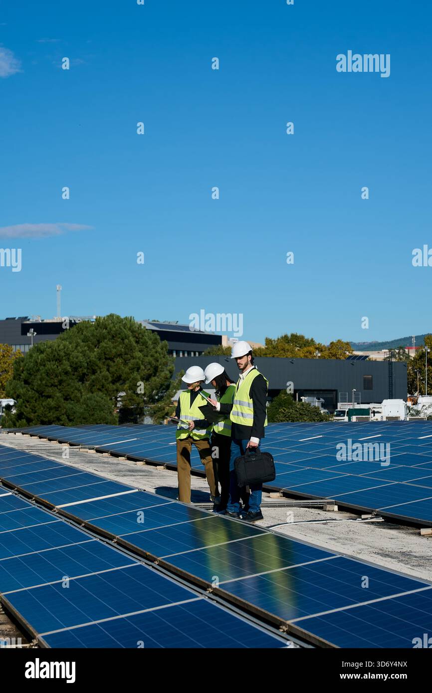 Engineers team inspecting rooftop solar panels on building Stock Photo