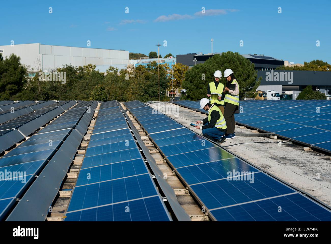 Engineers inspecting solar panels on a factory rooftop Stock Photo